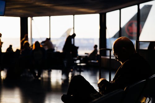 Free Silhouette of People Sitting Waiting to Board Stock Photo