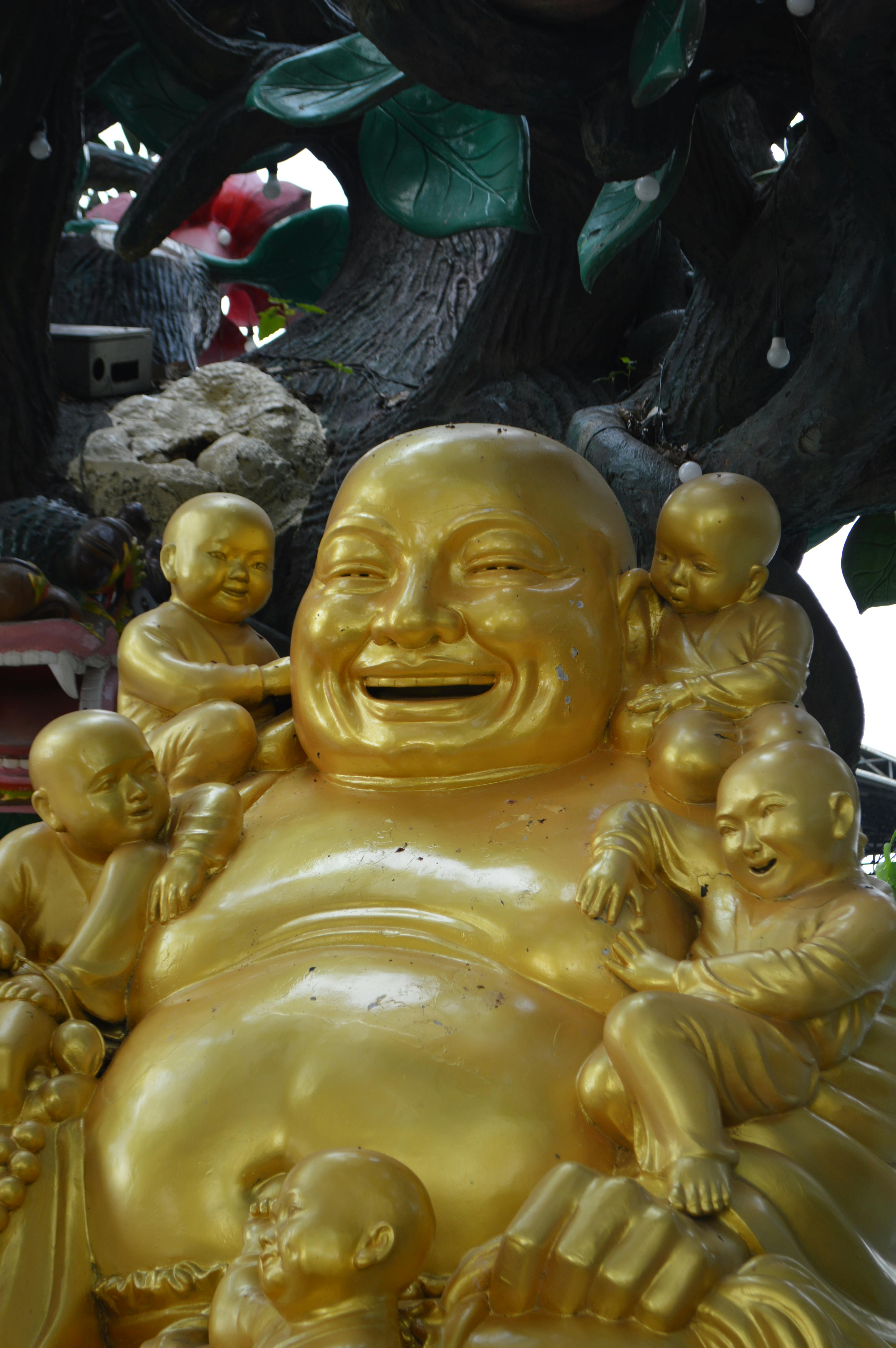 Golden Laughing Buddha surrounded by joyous child figures, symbolizing abundance and happiness.