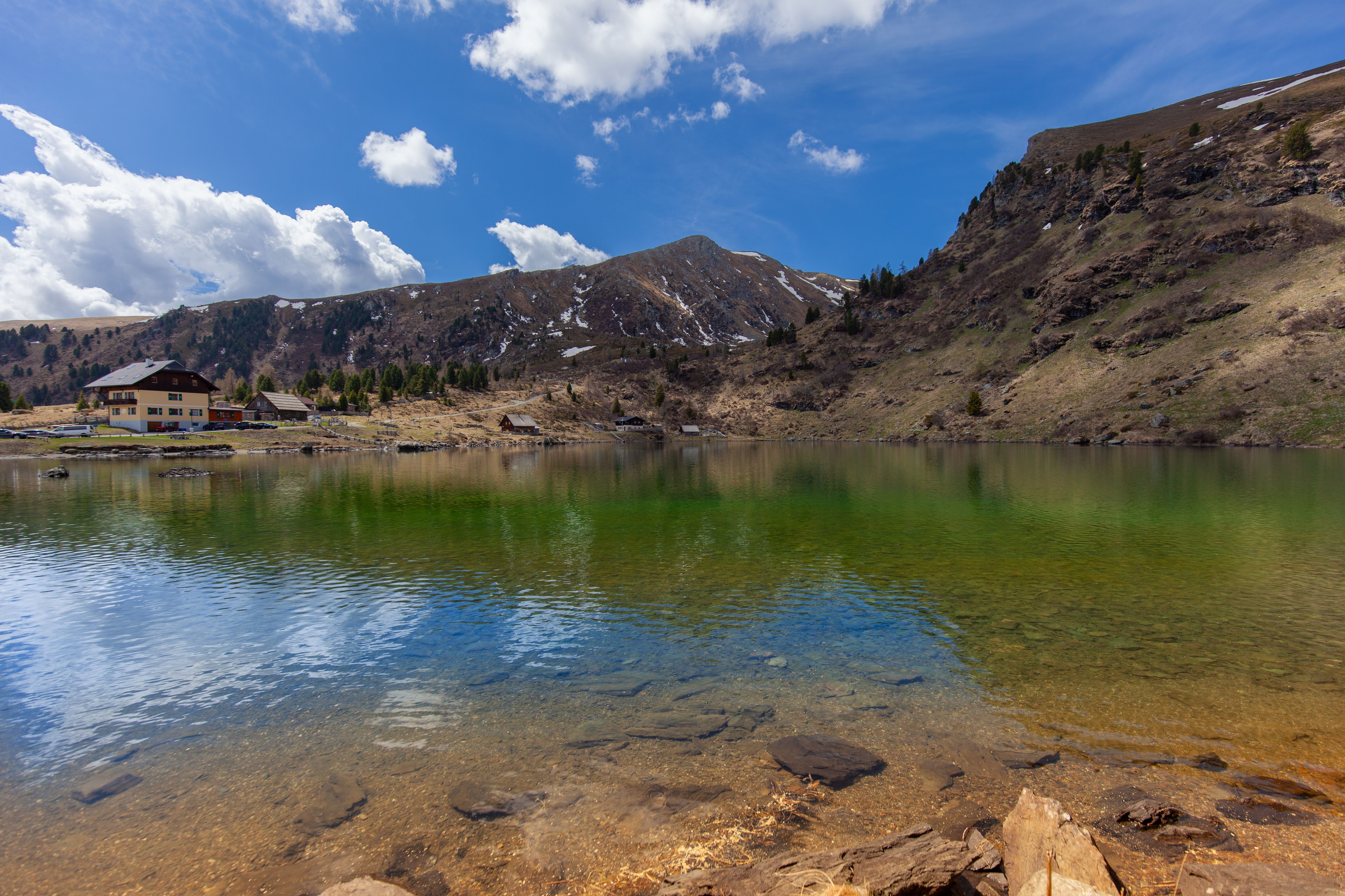 Beautiful mountain lake with clear water reflecting the sky, lodge nearby.