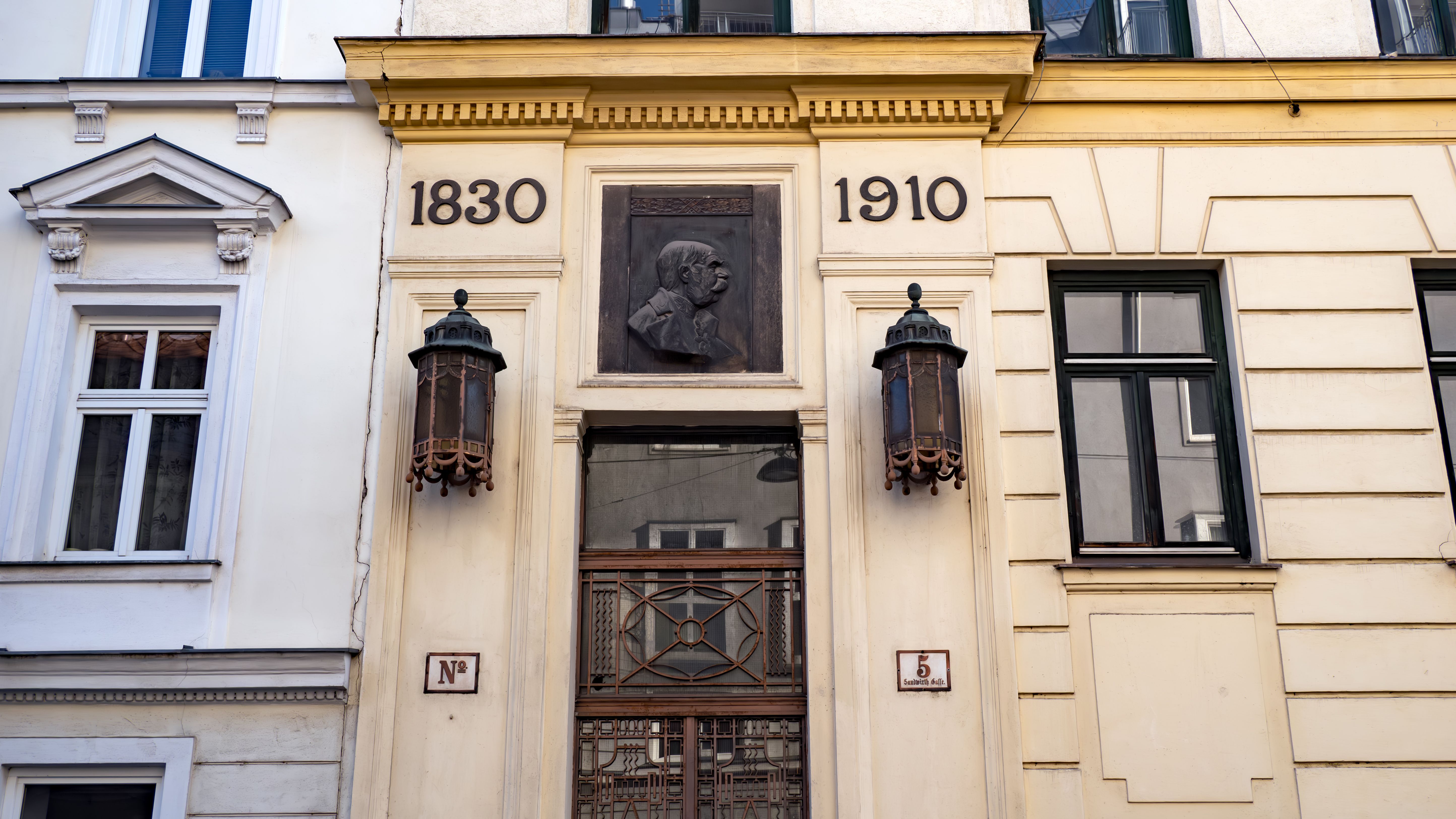 Elegant historic building facade showcasing the years 1830 and 1910 in Vienna, Austria.