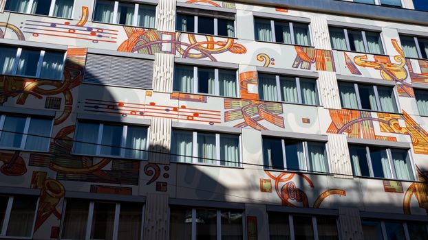 Vibrant mural art on building façade with windows in Vienna, Austria, showcasing abstract designs.