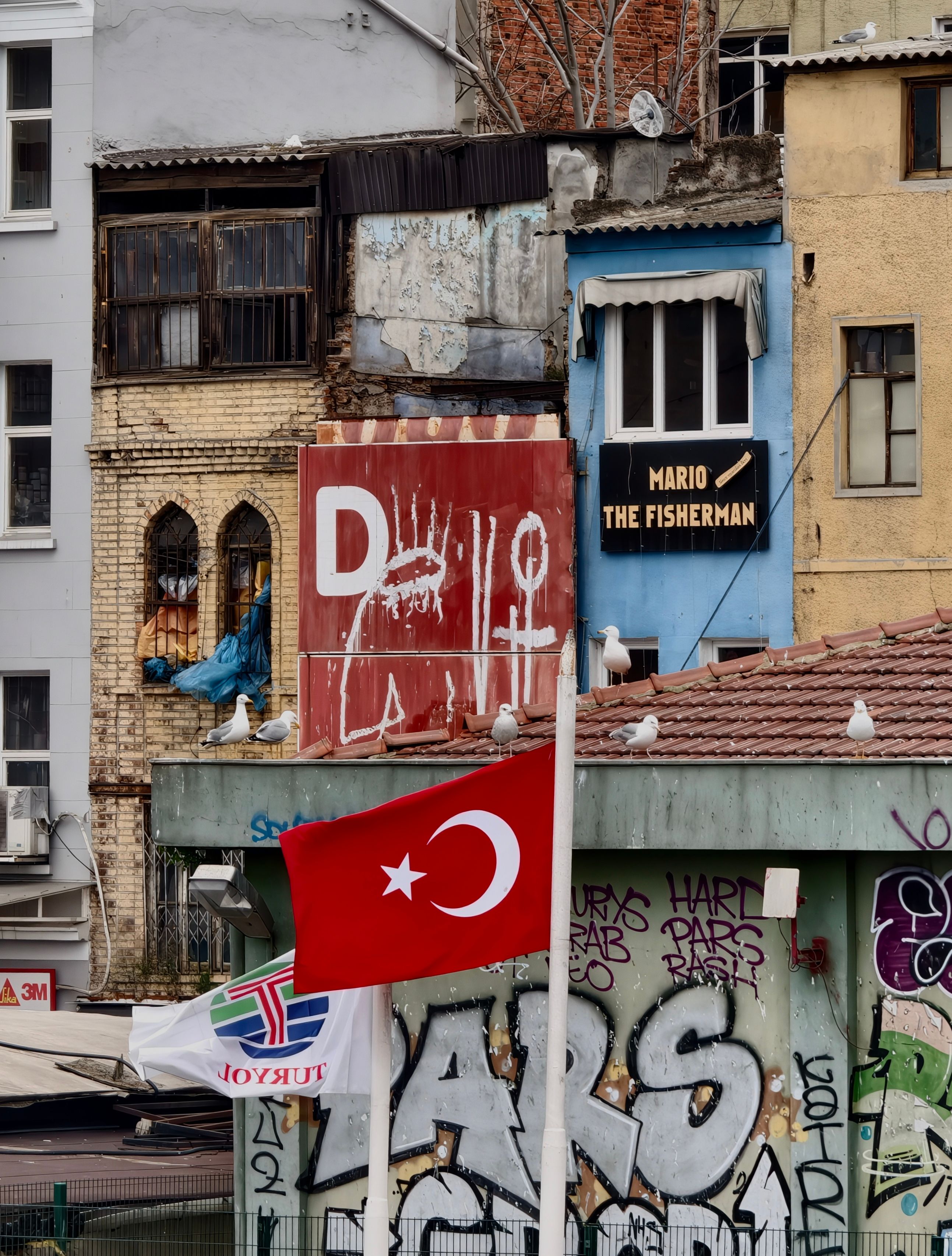 Urban street view in İstanbul showcasing buildings, graffiti, and Turkish flag.