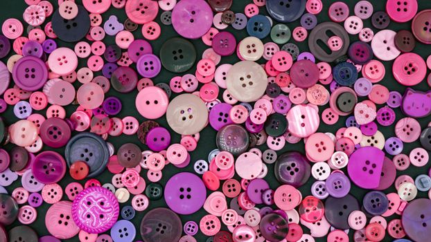 Vibrant collection of different sized and colored buttons in shades of pink and purple.