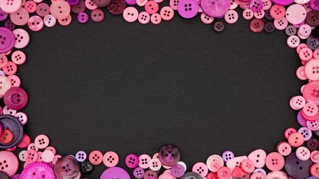 Assorted colorful buttons arranged around a black background, perfect for DIY projects.