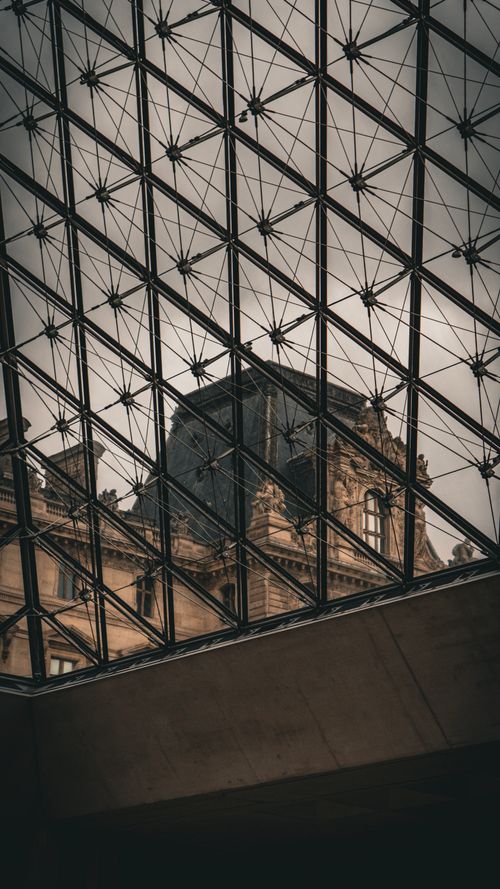 Free Classic view of Louvre Museum seen through the modern glass pyramid structure in Paris, France. Stock Photo