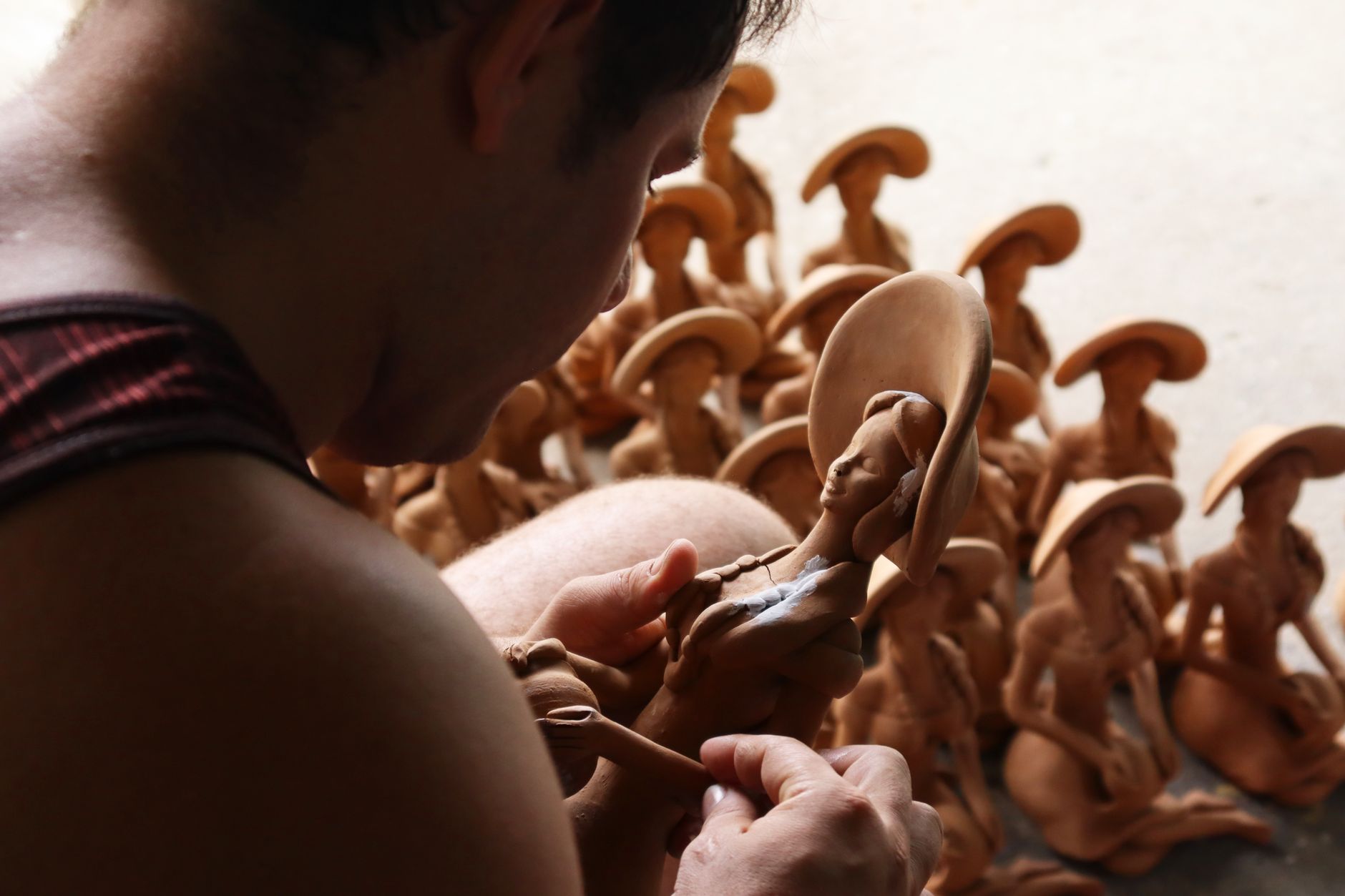 Close-up of an artisan crafting clay sculptures in a workshop setting.
