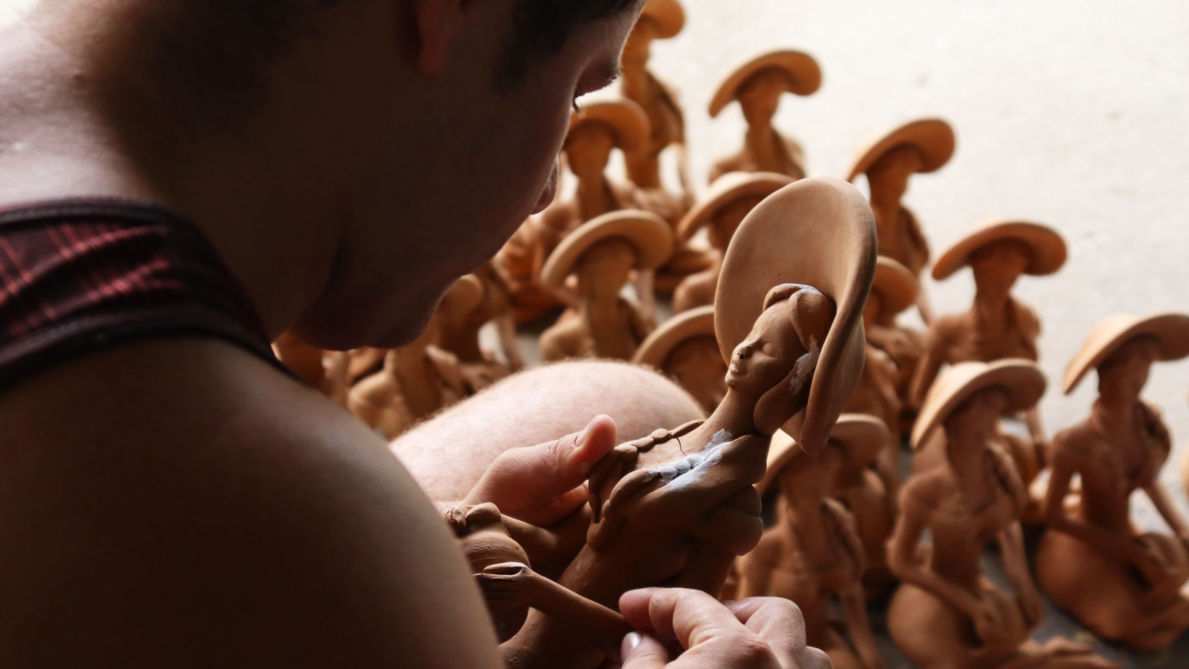 Close-up of an artisan crafting clay sculptures in a workshop setting.