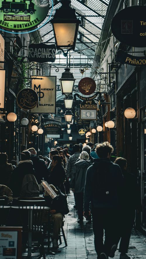Free A bustling covered passage in Paris, France, with people and vintage shop signs lining the walkway. Stock Photo