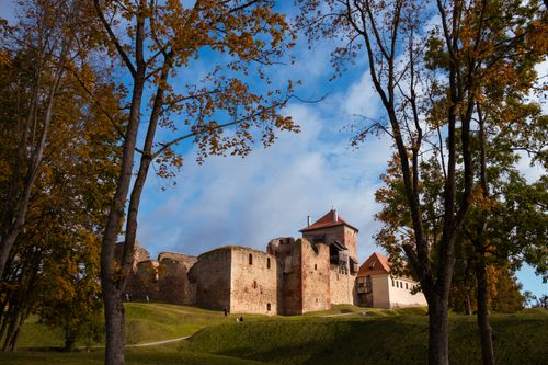 Free Discover Bauska Castle surrounded by vibrant autumn foliage in Latvia's picturesque countryside. Stock Photo