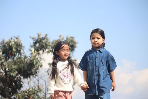 Free Two cheerful children holding hands, enjoying a sunny day outdoors. Stock Photo