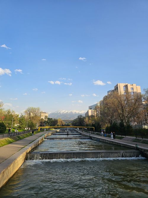 Free City scene featuring a canal, modern architecture, and distant mountains. Stock Photo