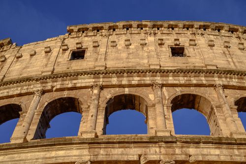 Free Detailed view of the Colosseum's ancient architecture in Rome under a clear blue sky. Stock Photo