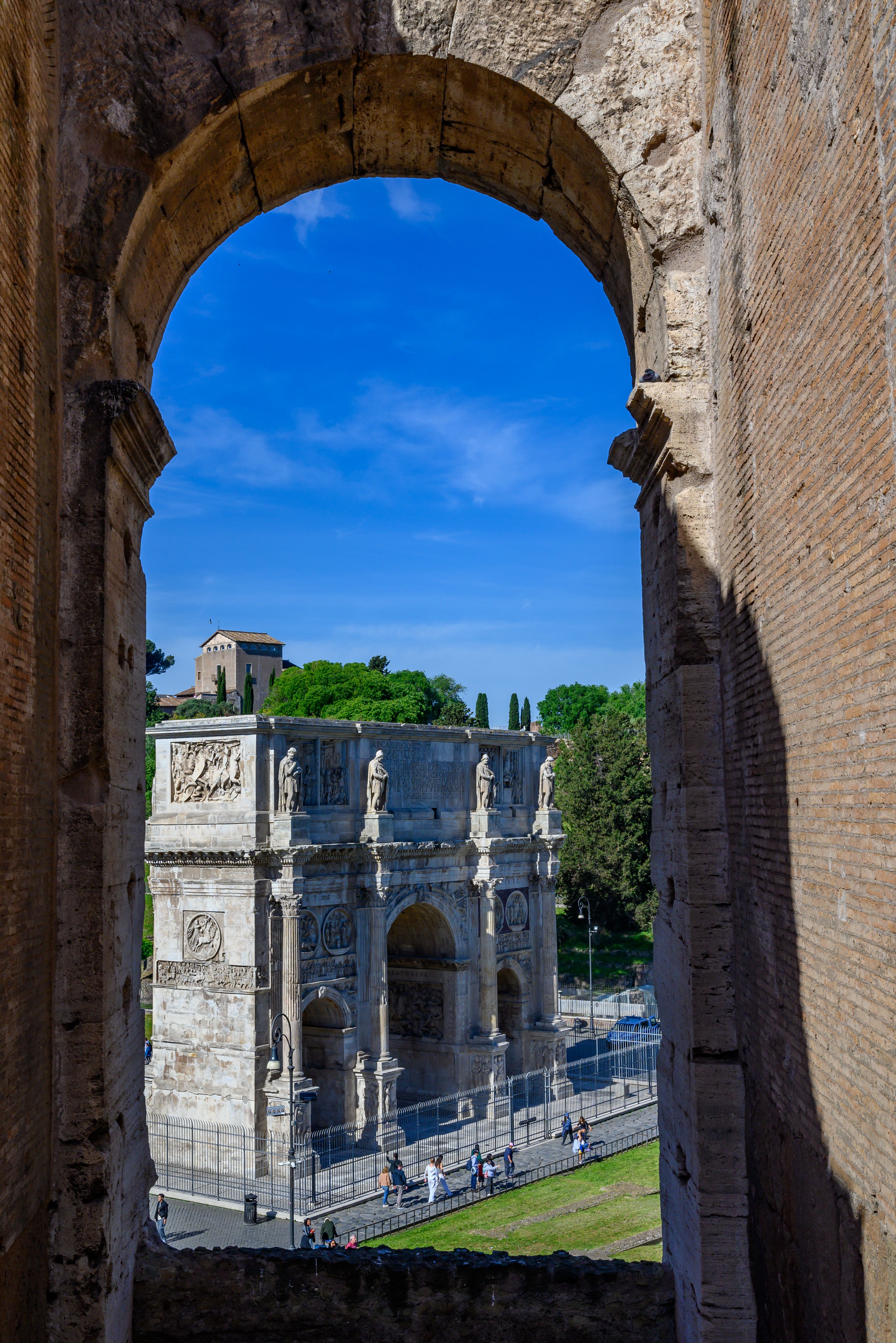 Fotomural El Arco de Constantino enmarcado por ruinas antiguas en Roma, Lacio, ofreciendo una impresionante vista histórica.