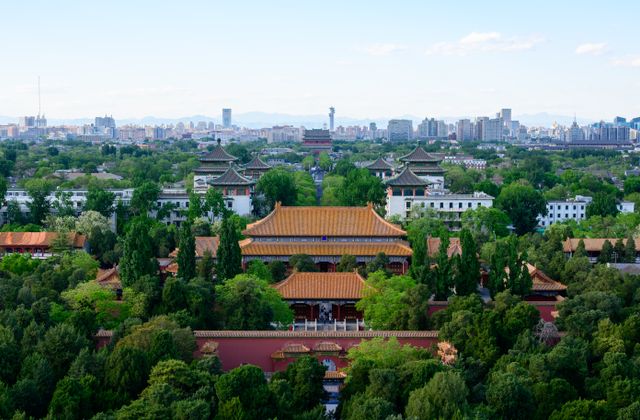 A stunning aerial view of ancient Chinese architecture with Beijing's city skyline in the background. — arriving in Beijing