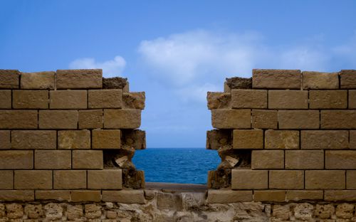 Free A stone wall with a gap overlooks the blue Mediterranean Sea under a clear sky. Stock Photo
