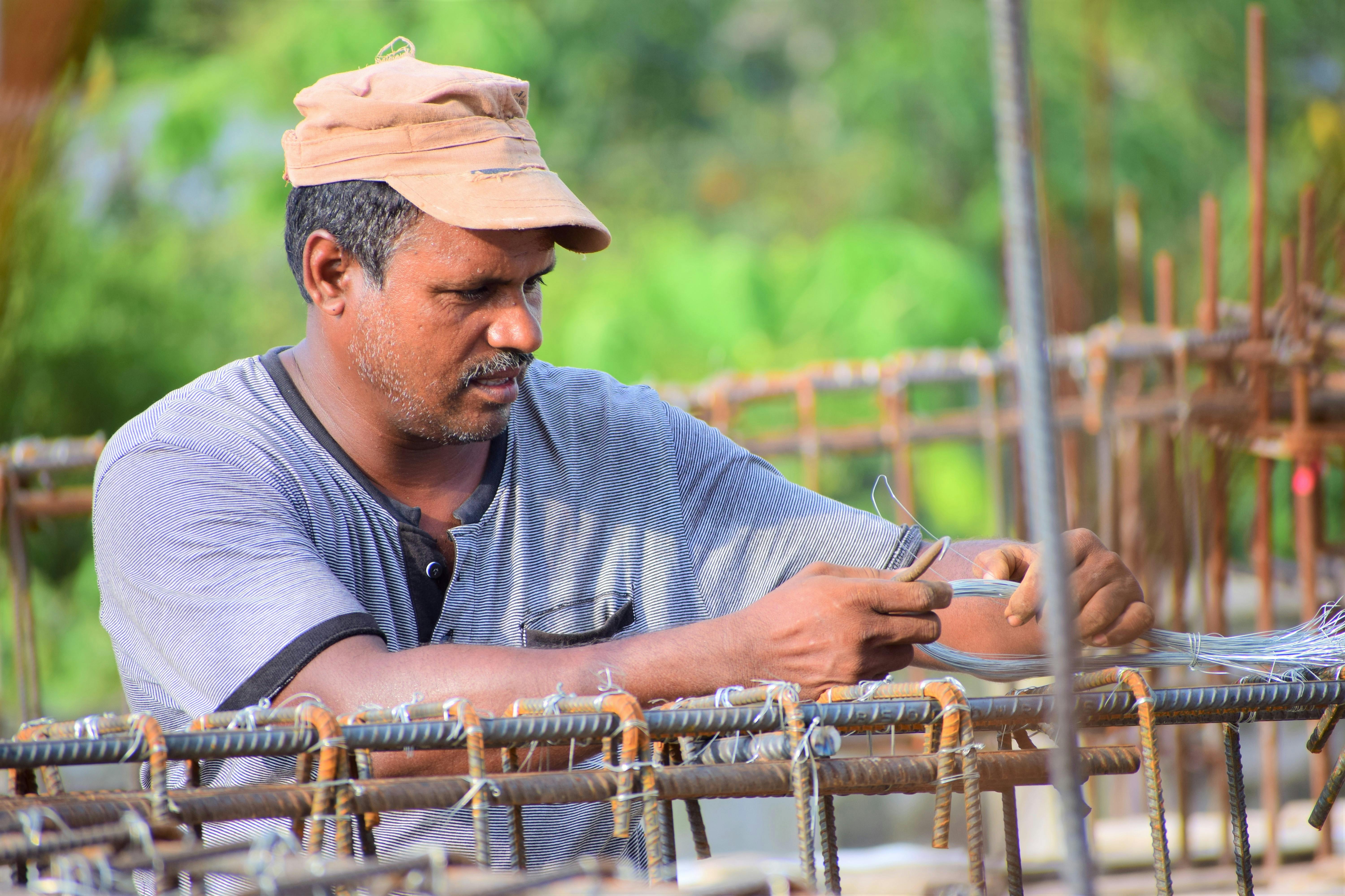 Un ouvrier du bâtiment consciencieux, en train de fixer des barres d'armature sur un chantier au Bangladesh, fait preuve d'habileté et de concentration.