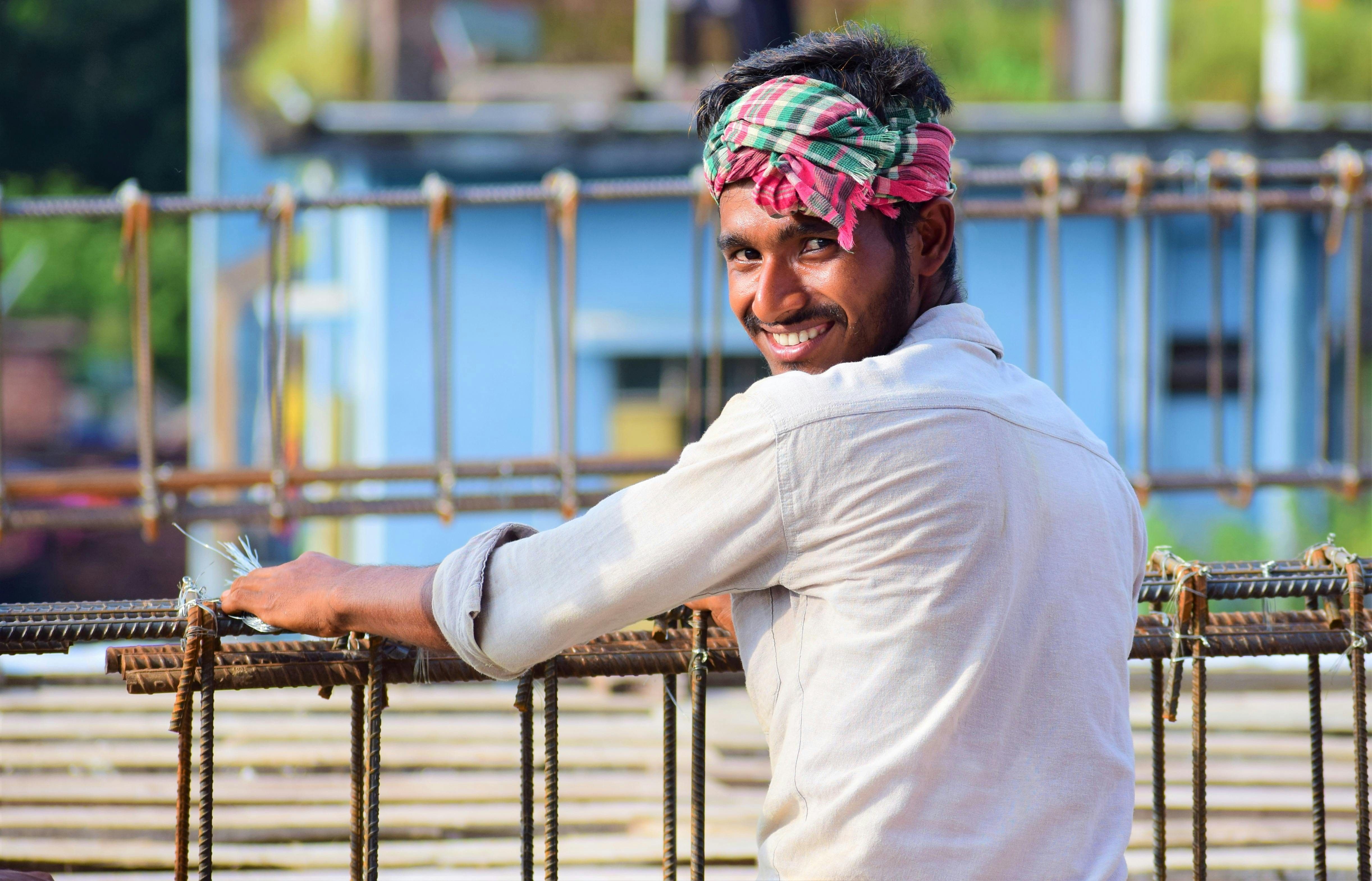 A cheerful construction worker smiles while working outdoors in Bangladesh.