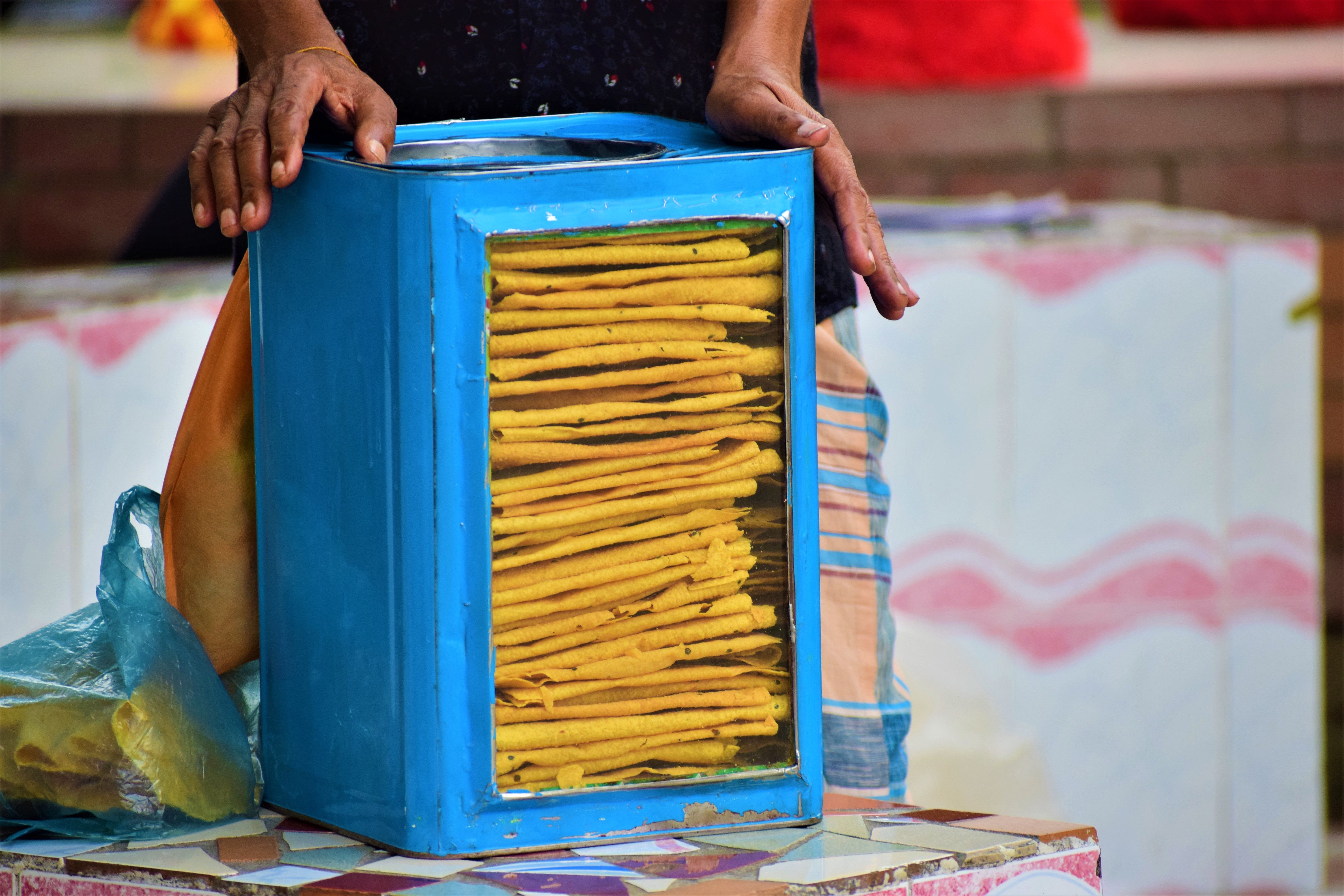 A street vendor showing traditional Bangladeshi snacks in a blue glass box. Captured in Mymensingh Division.