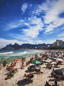 Vibrant scene of Ipanema Beach filled with people and umbrellas on a sunny day.