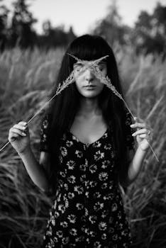 这幅迷人的黑白肖像画描绘了一名妇女在田野里手持草束的景象