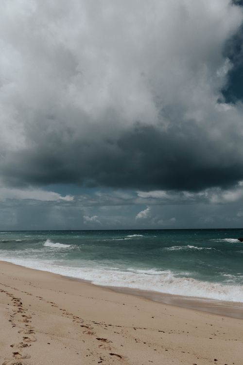 Free Moody beach scene with storm clouds and waves crashing on the shore. Stock Photo