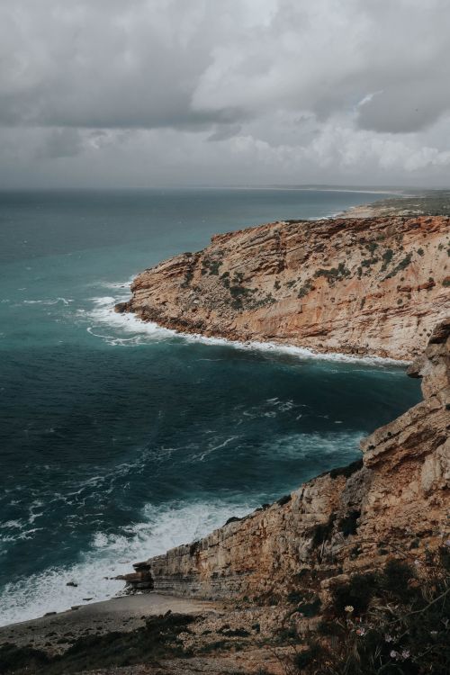 Free Dramatic cliffs meet powerful ocean waves under a cloudy sky, creating a breathtaking coastal view. Stock Photo
