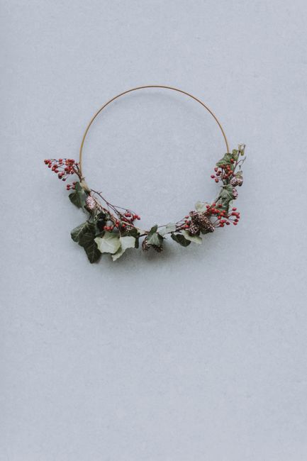 A simple floral wreath with leaves and flowers on a light, neutral backdrop.