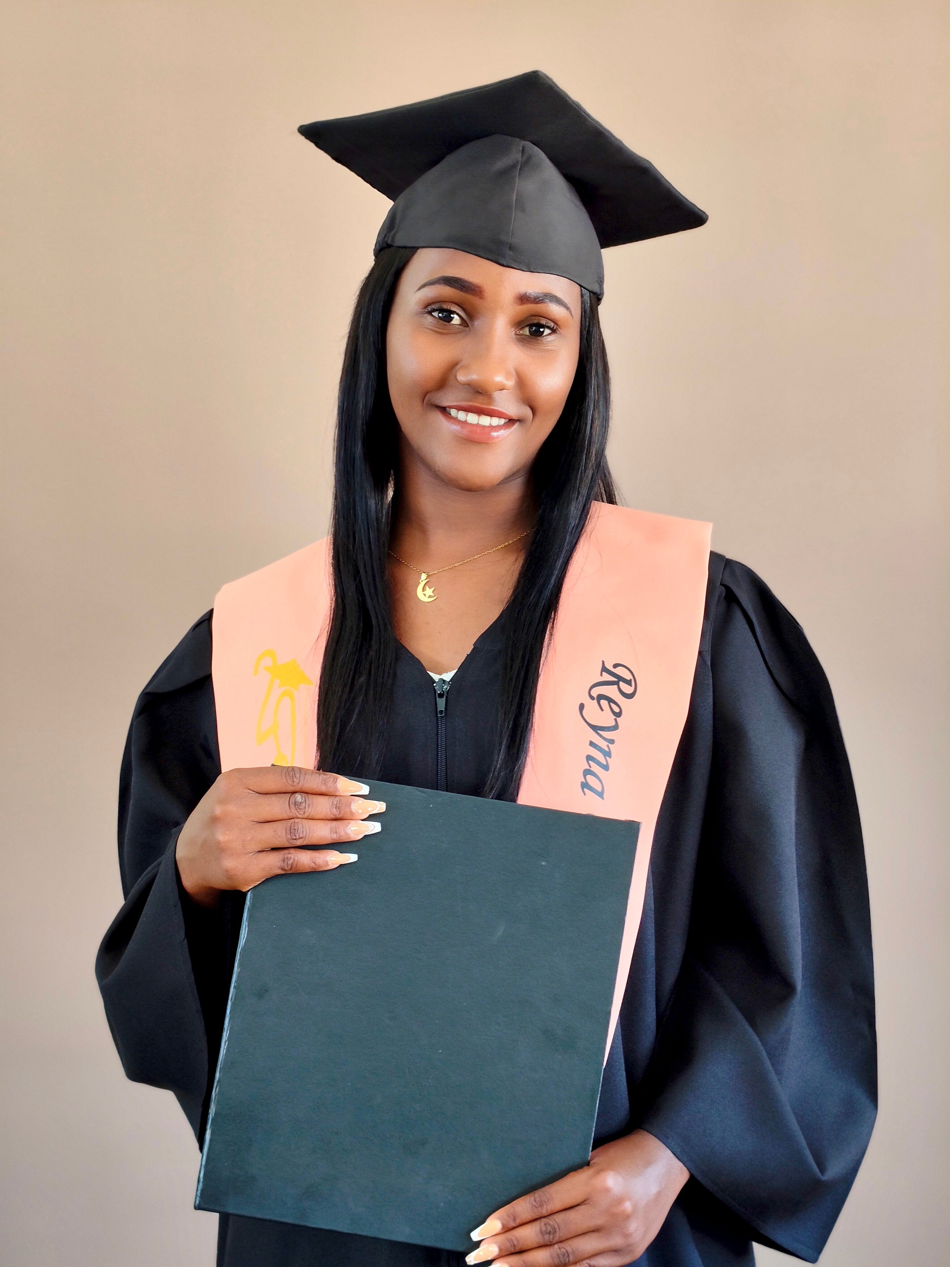 Confident graduate in cap and gown holding diploma, celebrating academic achievement.