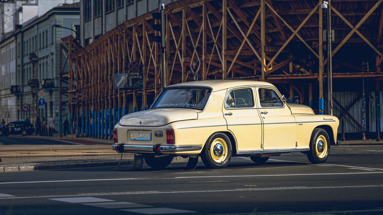 a classic vintage car parked at an urban street corner with wooden sca