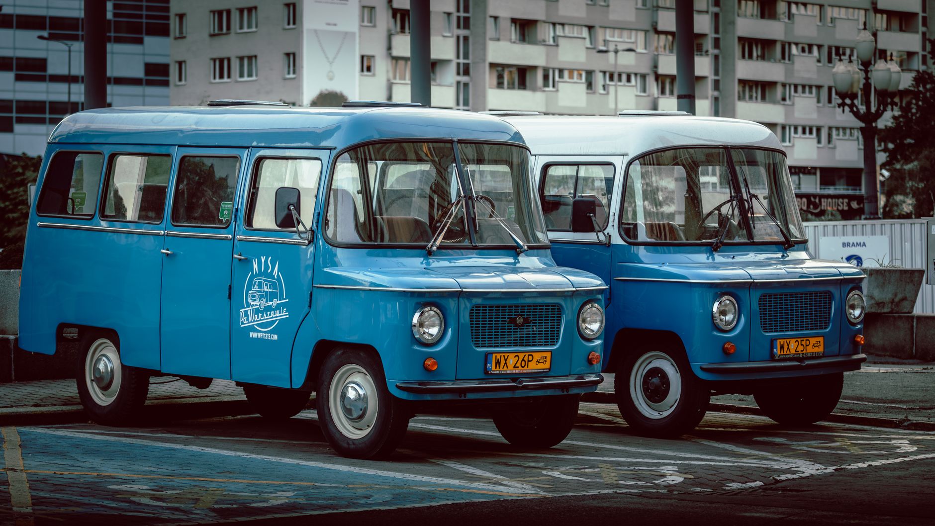 Nysa vans parked in a city street, showcasing vintage automotive style.