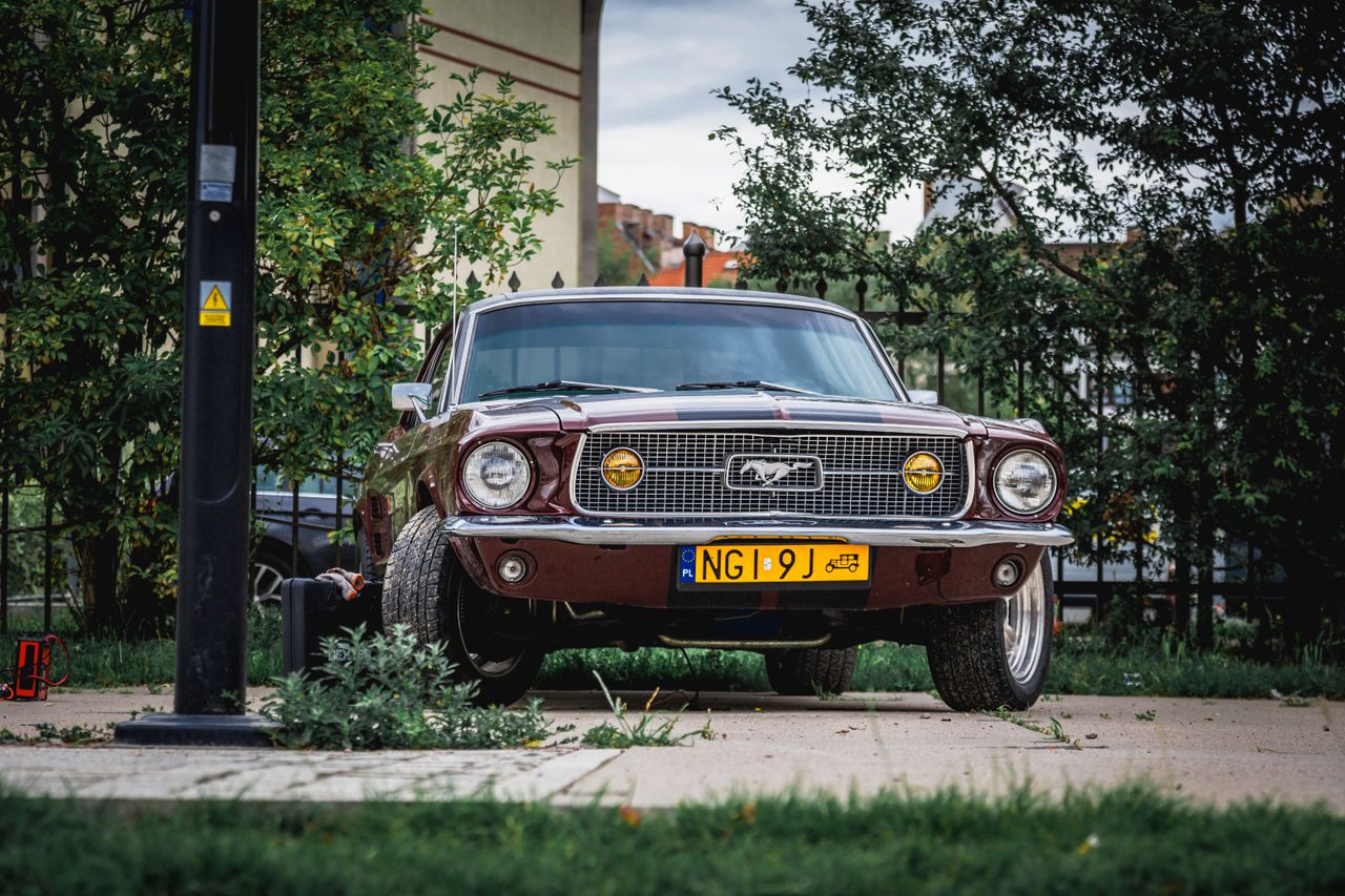 front view of a vintage red ford mustang parked outdoors showcasing it