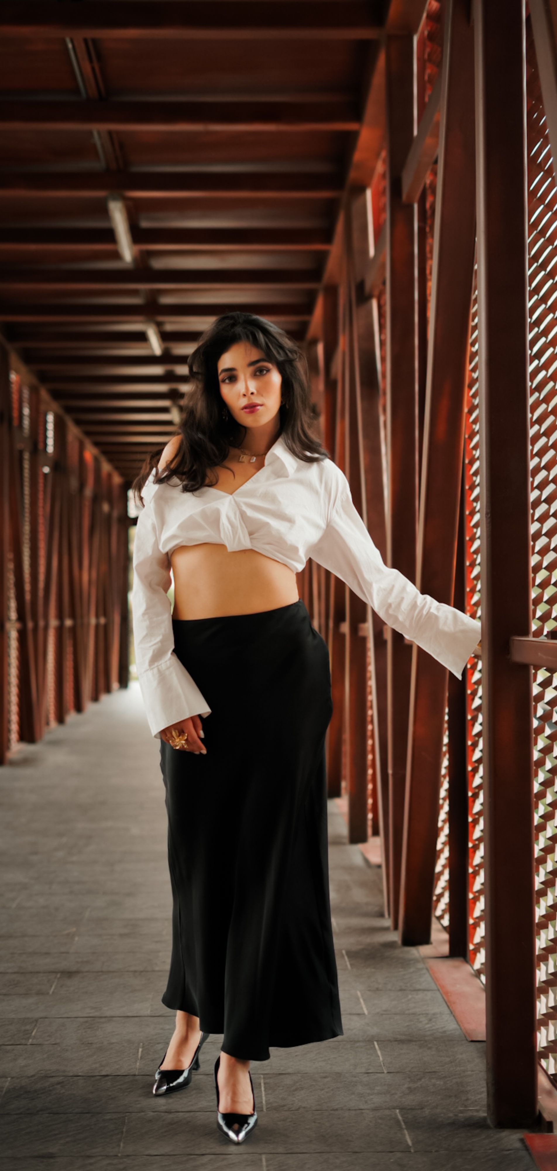 Stylish young woman posing confidently in a contemporary indoor walkway with geometric patterns.