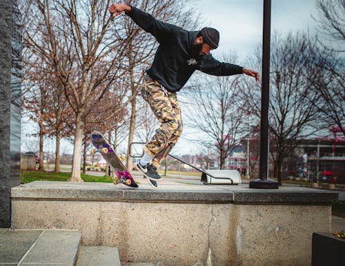 Free Man in Black Jacket and Brown Pants Jumping on Skateboard Stock Photo