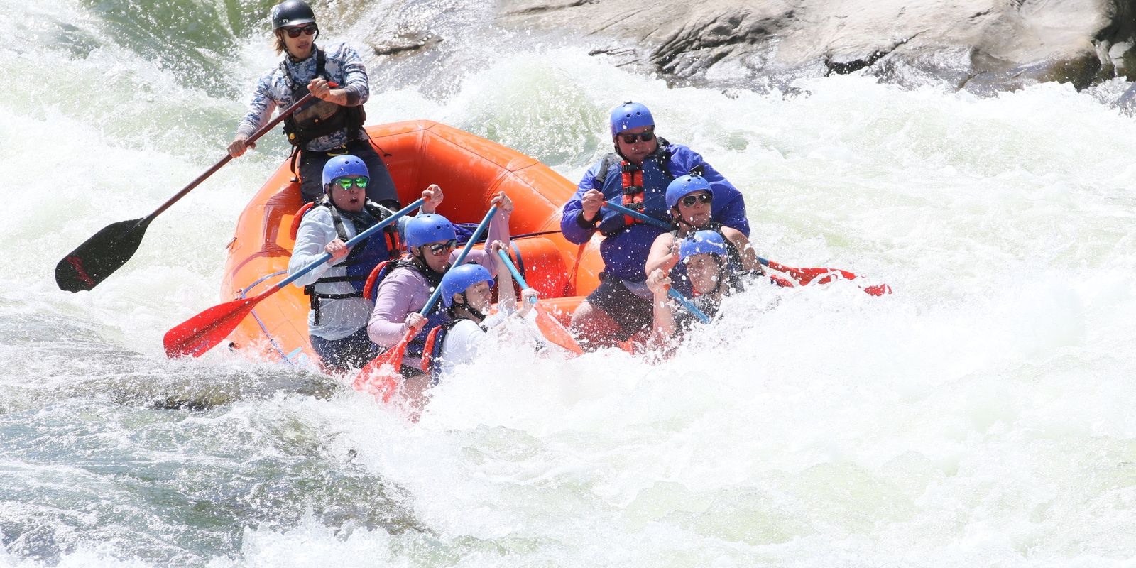 A group paddling hard through powerful whitewater rapids