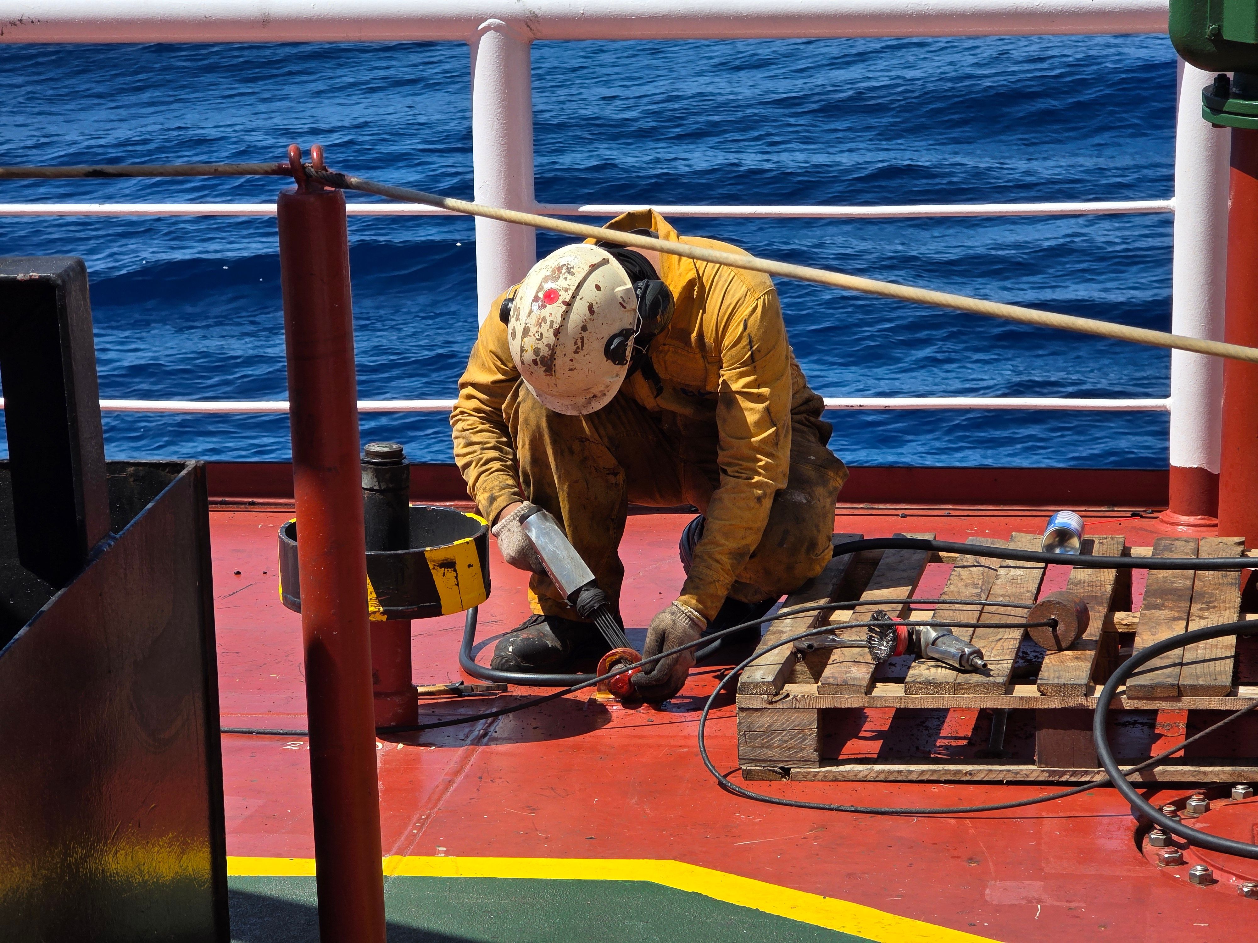 Maritime Worker Performing Maintenance on Ship Deck · Free Stock Photo