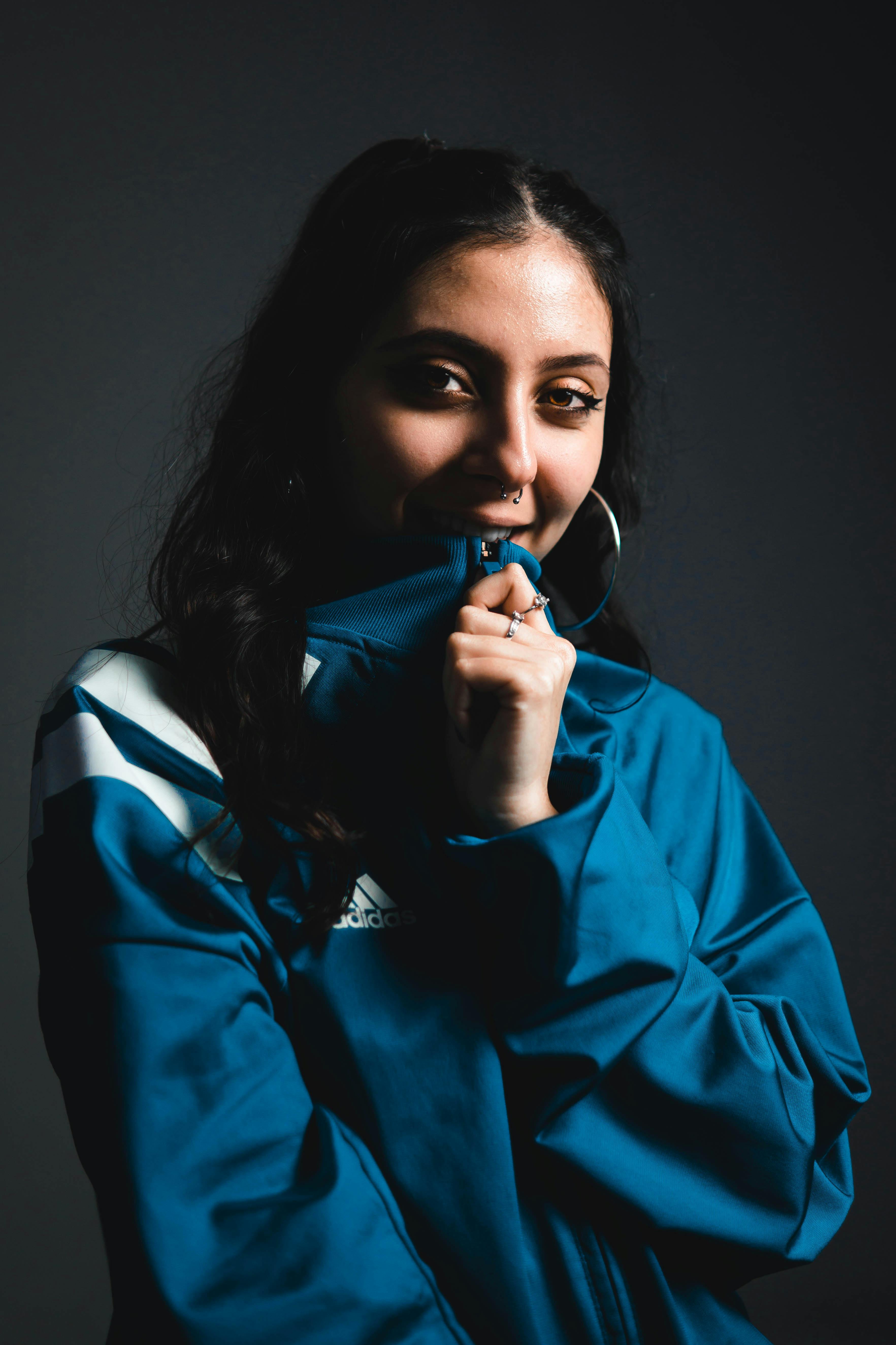 一位身穿蓝色夹克、神态泰然自若的自信年轻女子，在工作室拍摄肖像