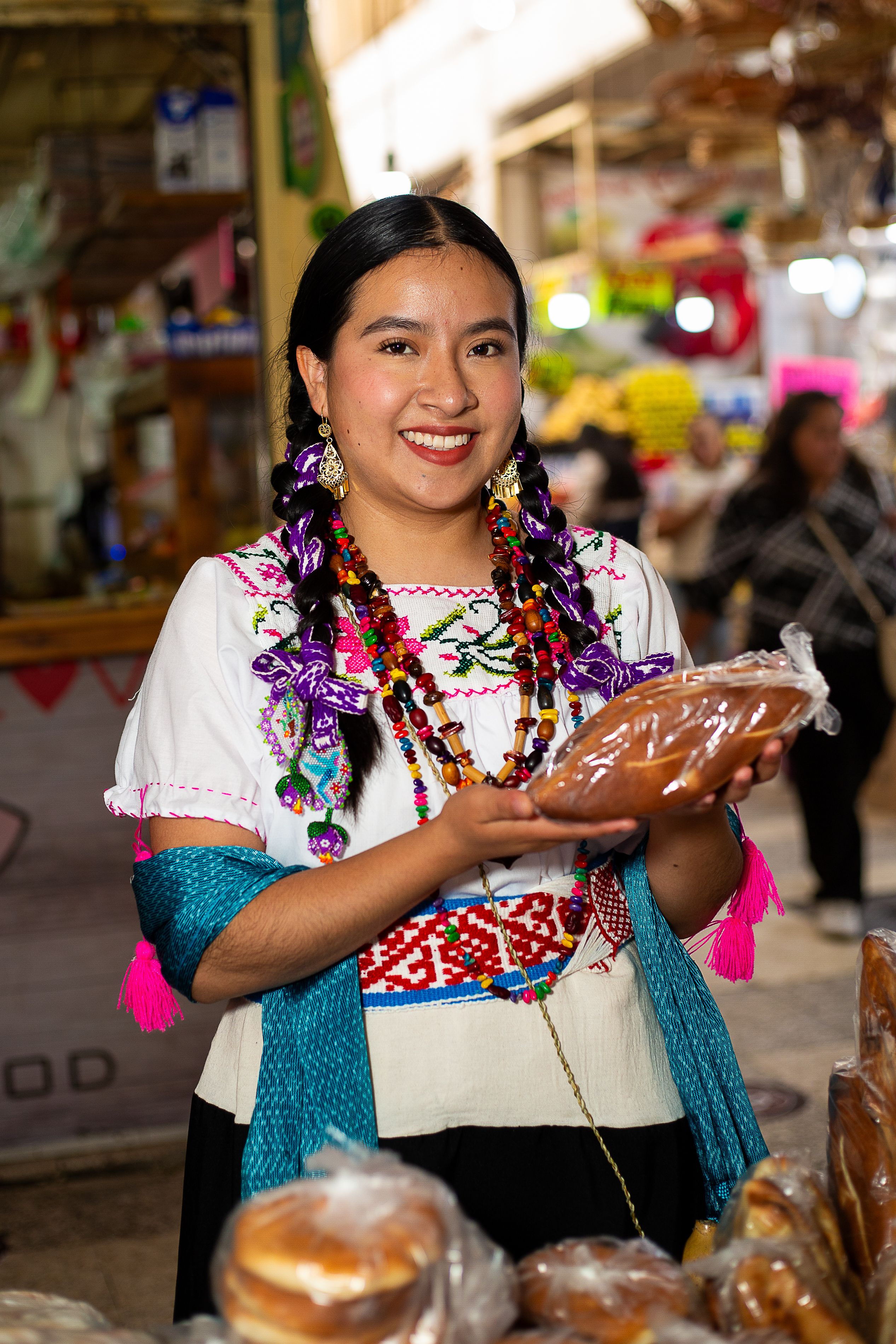 A woman in traditional attire presenting homemade bread at a bustling market.