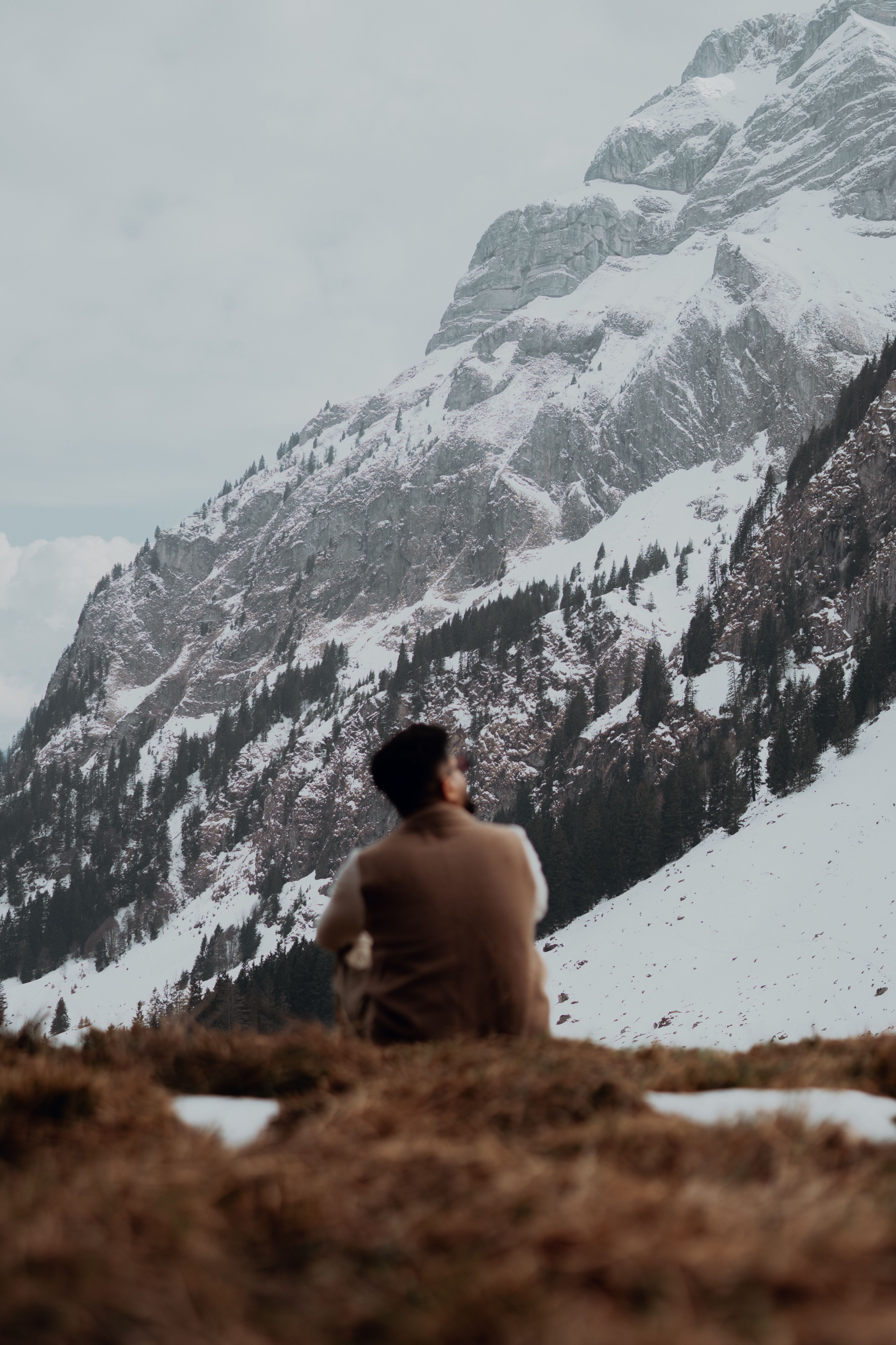 A person enjoys a serene moment overlooking snowy mountains in Alpnach, Switzerland.
