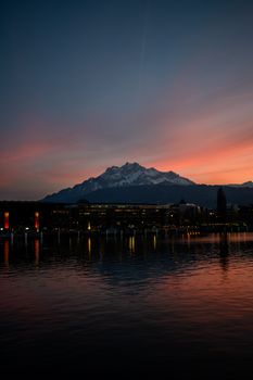 Stunning twilight view of Lucerne cityscape and Mount Pilatus at sunset reflecting on the lake.