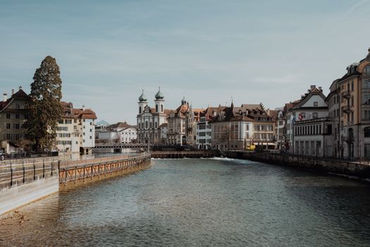 Charming view of Lucerne's iconic buildings alongside the Reuss river under a clear sky.
