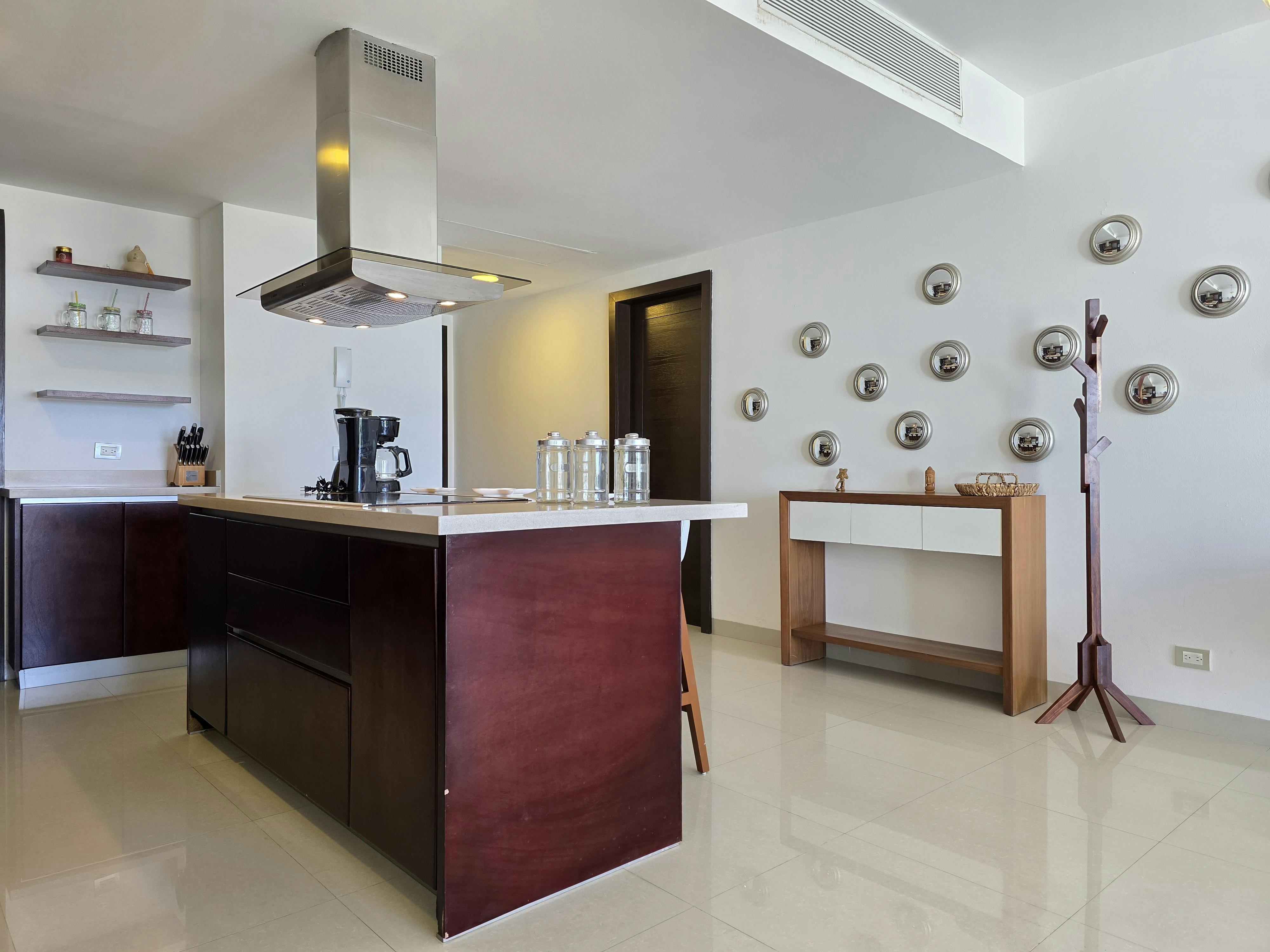 Sleek modern kitchen with central island, stainless steel decor, and wall-mounted art.