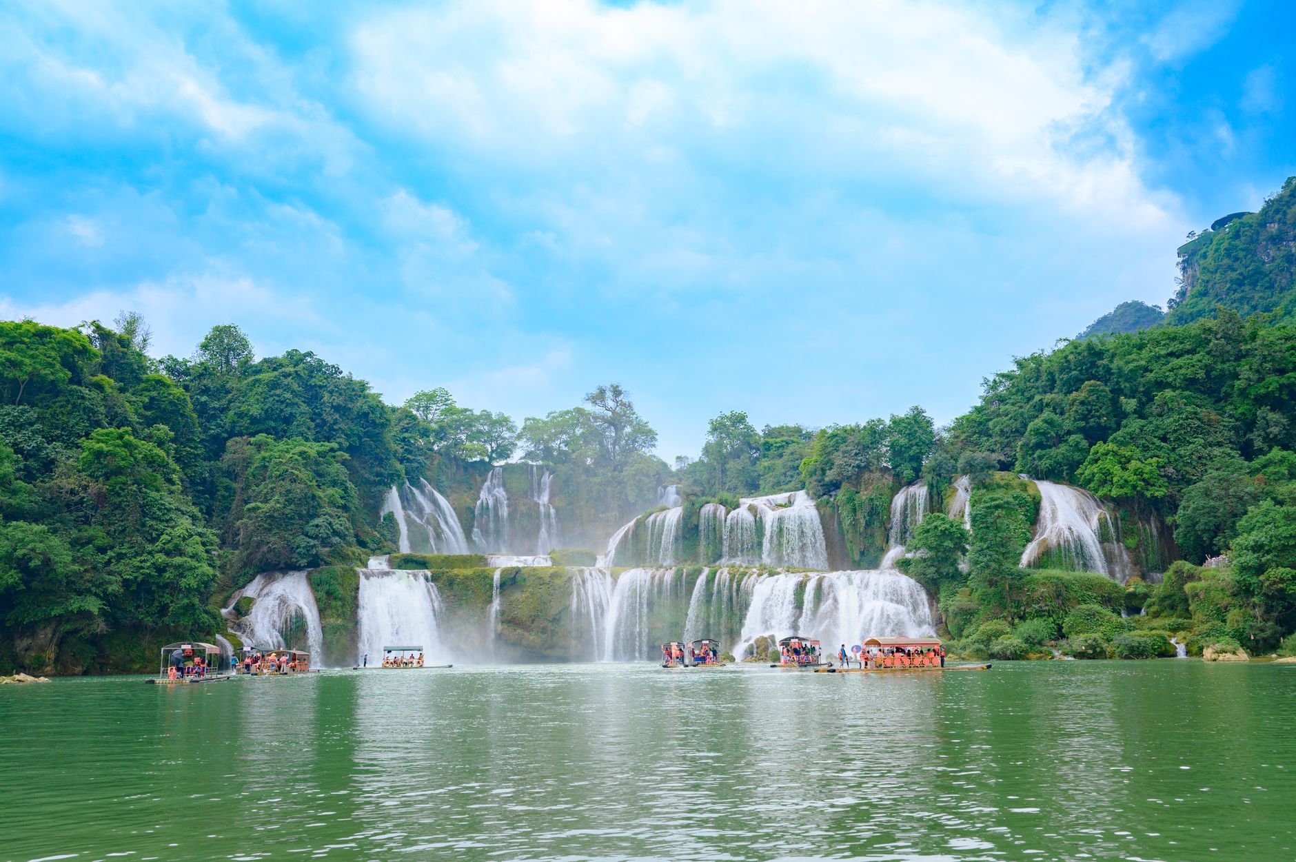A breathtaking view of Ban Gioc Waterfall in Cao Bằng, Vietnam, surrounded by lush greenery.