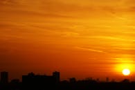 充满活力的橙色日落天空映衬着城市建筑剪影，捕捉到城市的宁静