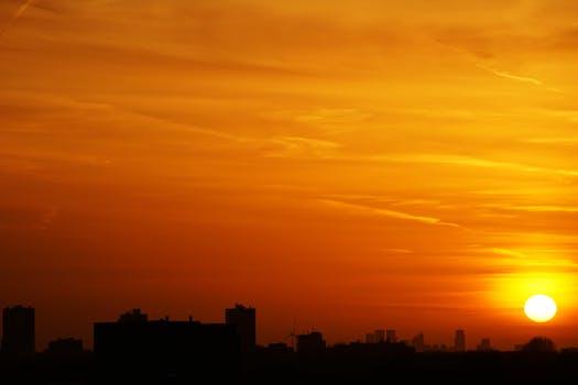 充满活力的橙色日落天空映衬着城市建筑剪影，捕捉到城市的宁静