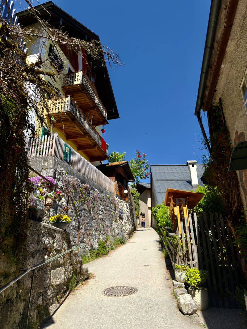 Alee pitorească în Hallstatt, Austria, cu case colorate și flori vibrante