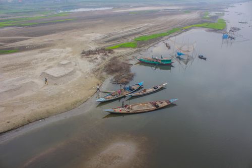 Free Aerial photo capturing traditional boats moored on a serene riverbank in rural Bangladesh. Stock Photo