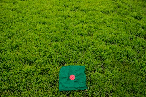Free Aerial view of Bangladeshi flag on lush green grass, symbolizing national pride. Stock Photo