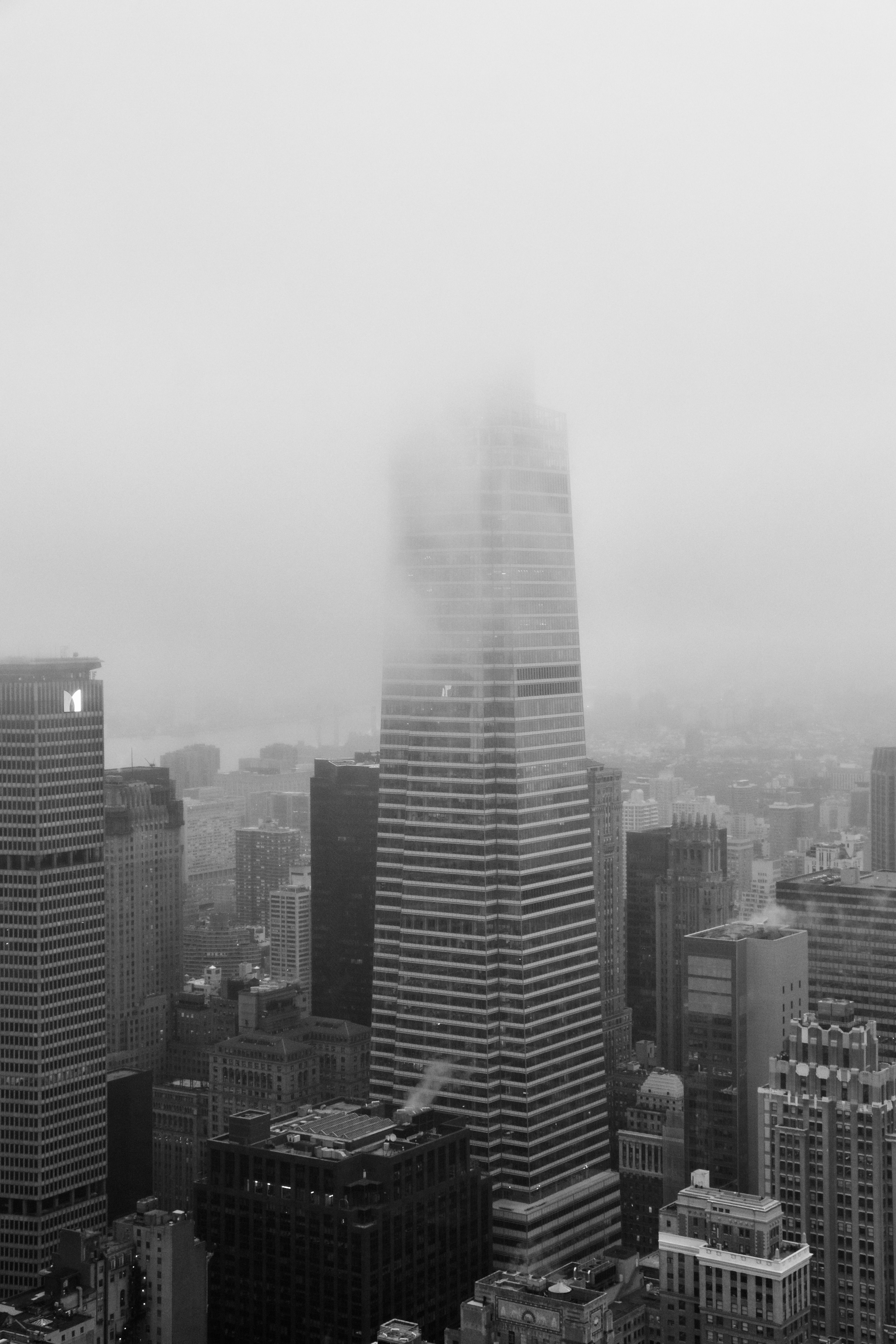 Black and white cityscape with fog enveloping tall skyscrapers, architectural beauty.