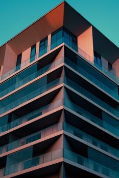 A sleek modern building with geometric design captured at sunset with vibrant lighting.