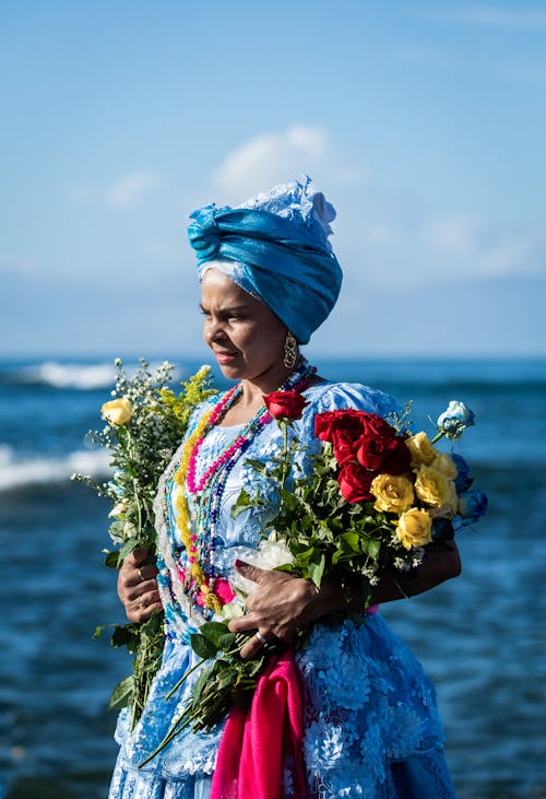 花の花束を保持している青と赤の花のドレスの女性